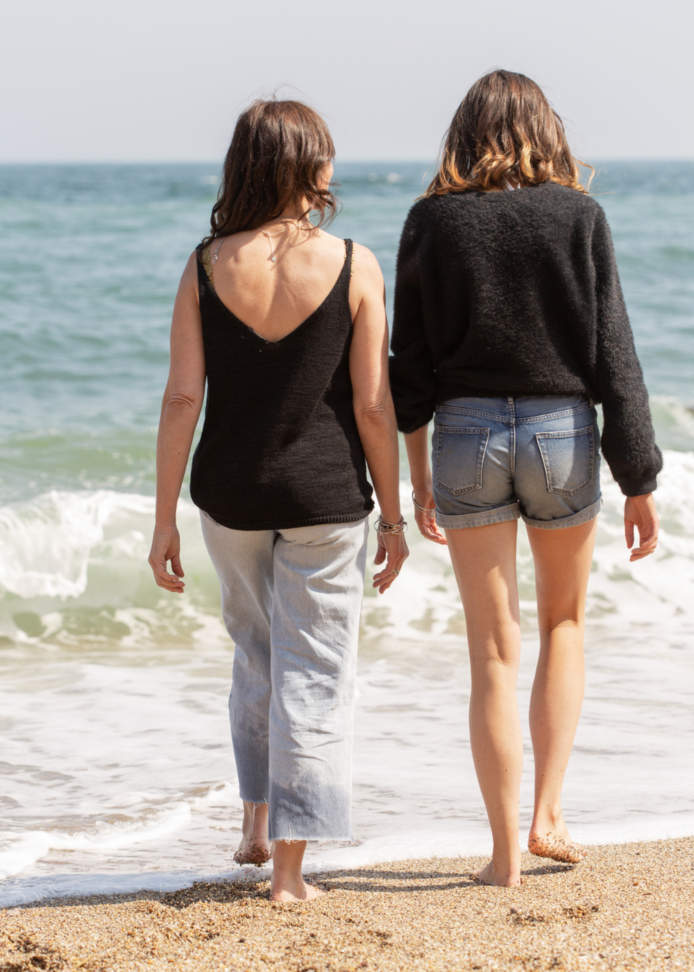 Helen Butler walking along the shoreline with a friend, reflecting the coastal inspiration behind Helen Butler Designs