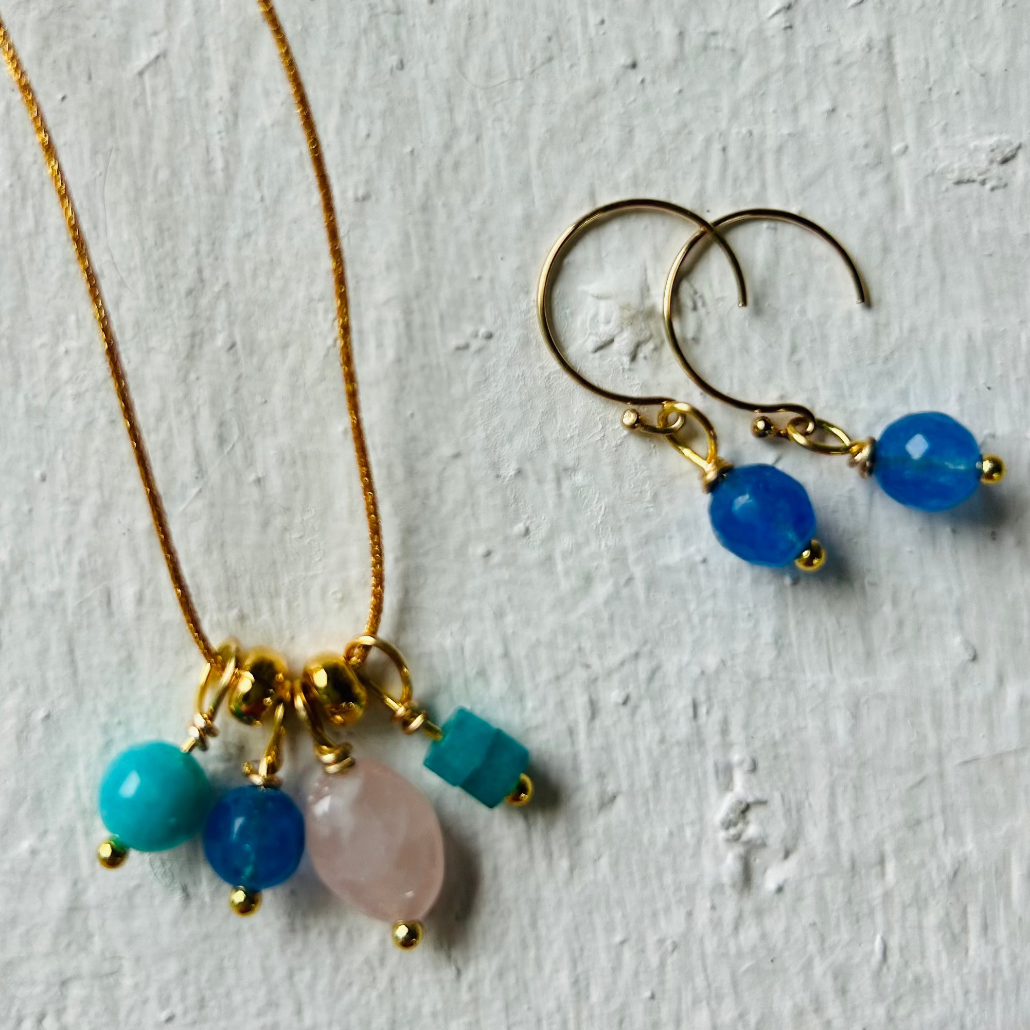 Jewelry set with necklace and earrings on a textured white surface
